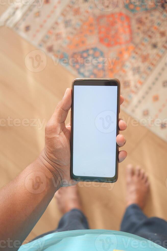 Hand holding a blank smartphone in a cozy indoor setting photo