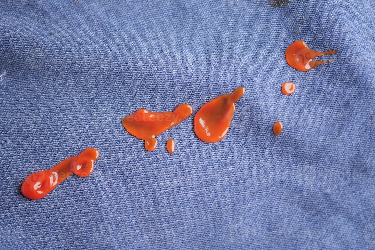 Red sauce splatters on blue fabric create vibrant contrast photo