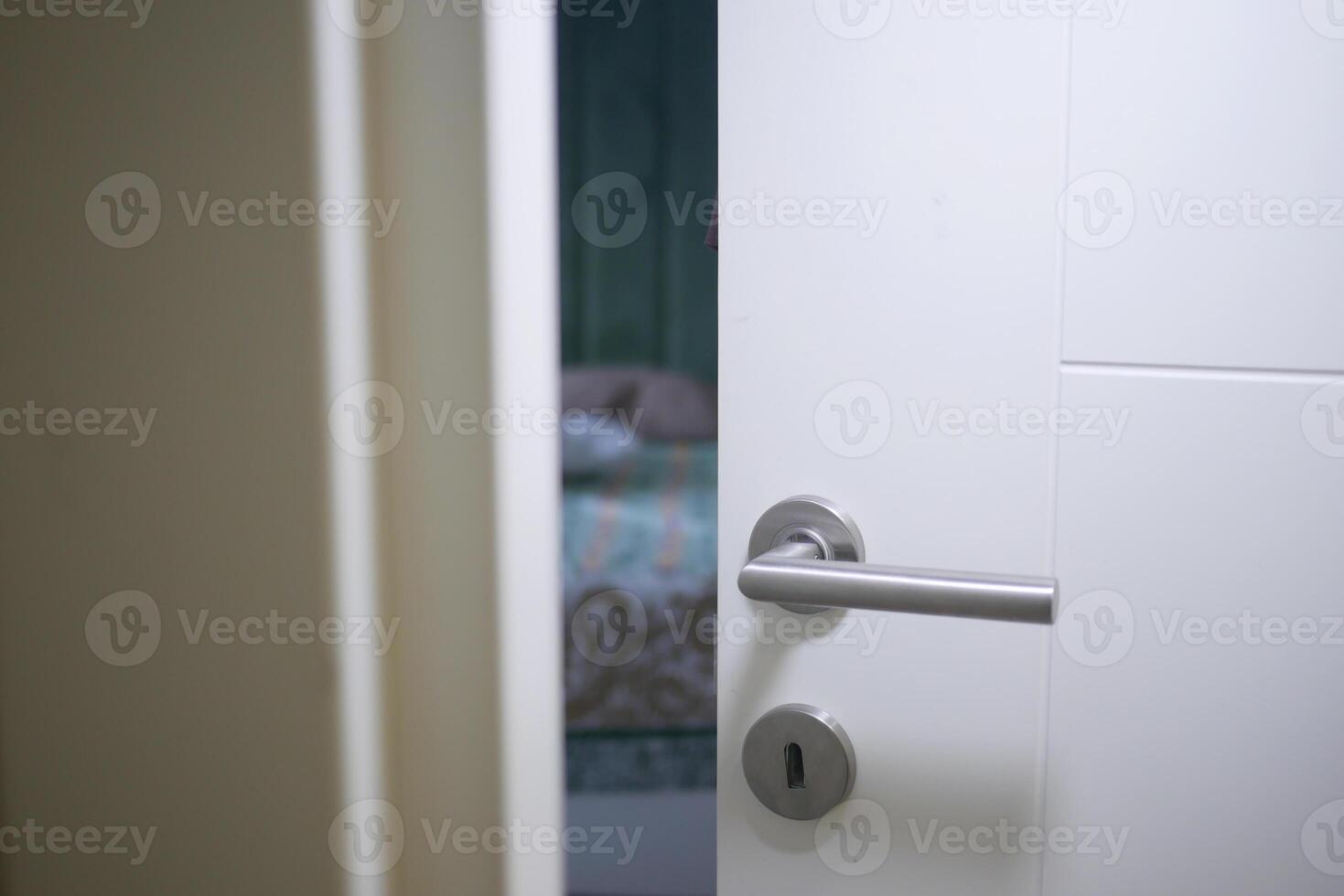 Door partially open revealing a softly lit bedroom interior photo