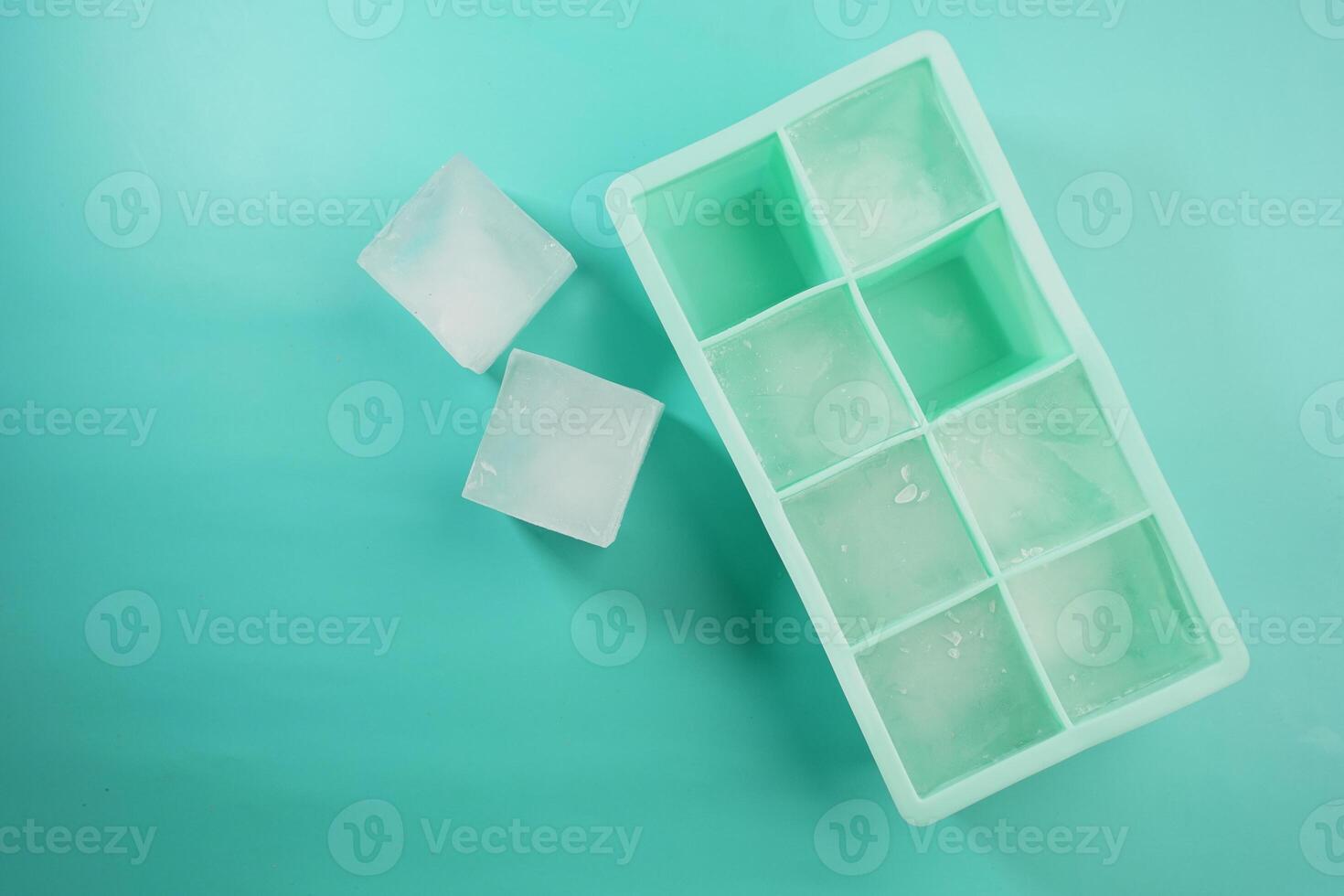 Ice cubes arranged neatly in a green ice tray on a flat surface photo