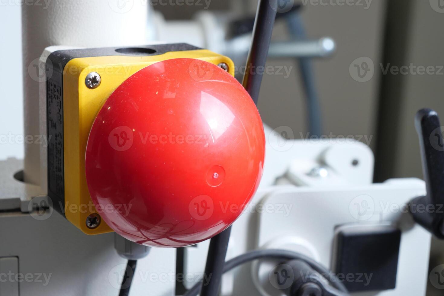 Red emergency stop button on machinery in a workshop setting photo