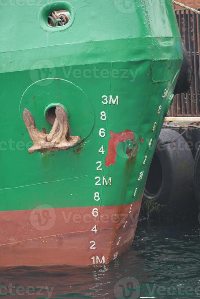 Cargo ship moored at dock with visible depth markings in morning light photo