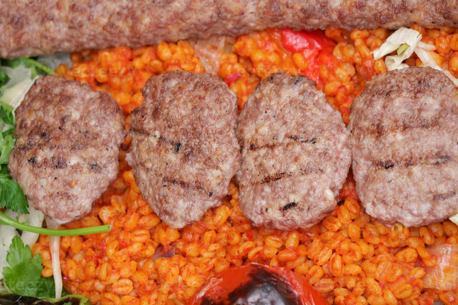 Grilled kebabs served on colorful spiced rice with vegetables photo