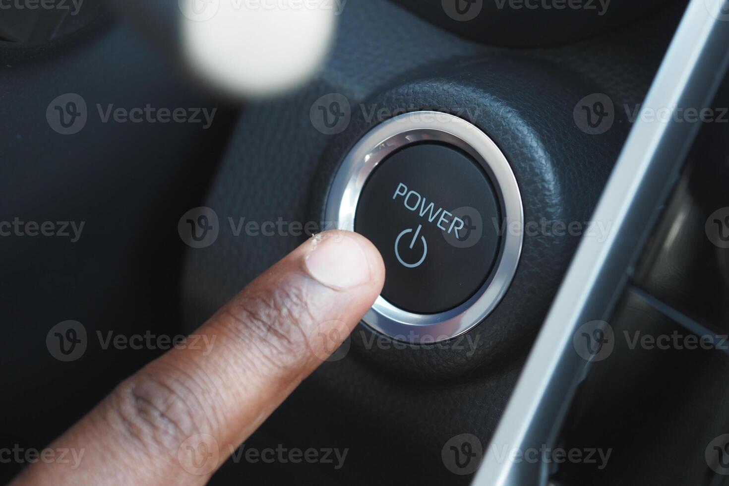 Hand pressing power button inside a car for ignition photo