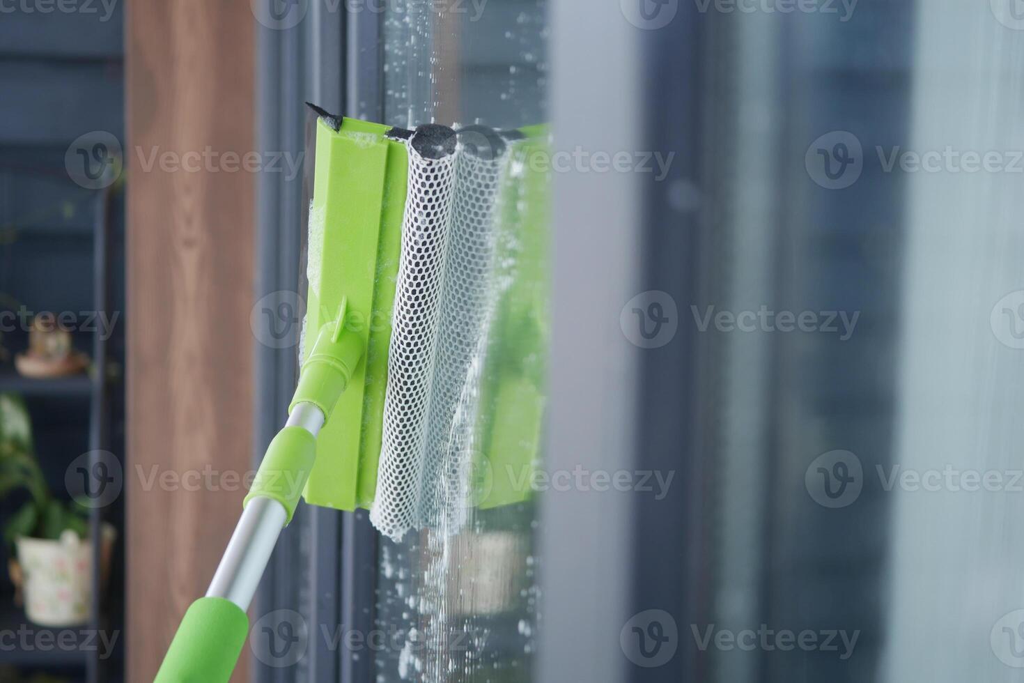Cleaning glass window with a squeegee in a modern home photo