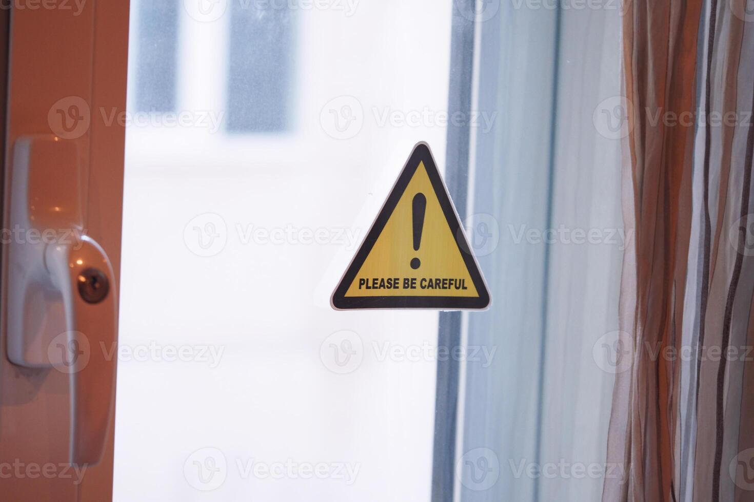 Warning sign reminding to exercise caution near open window photo