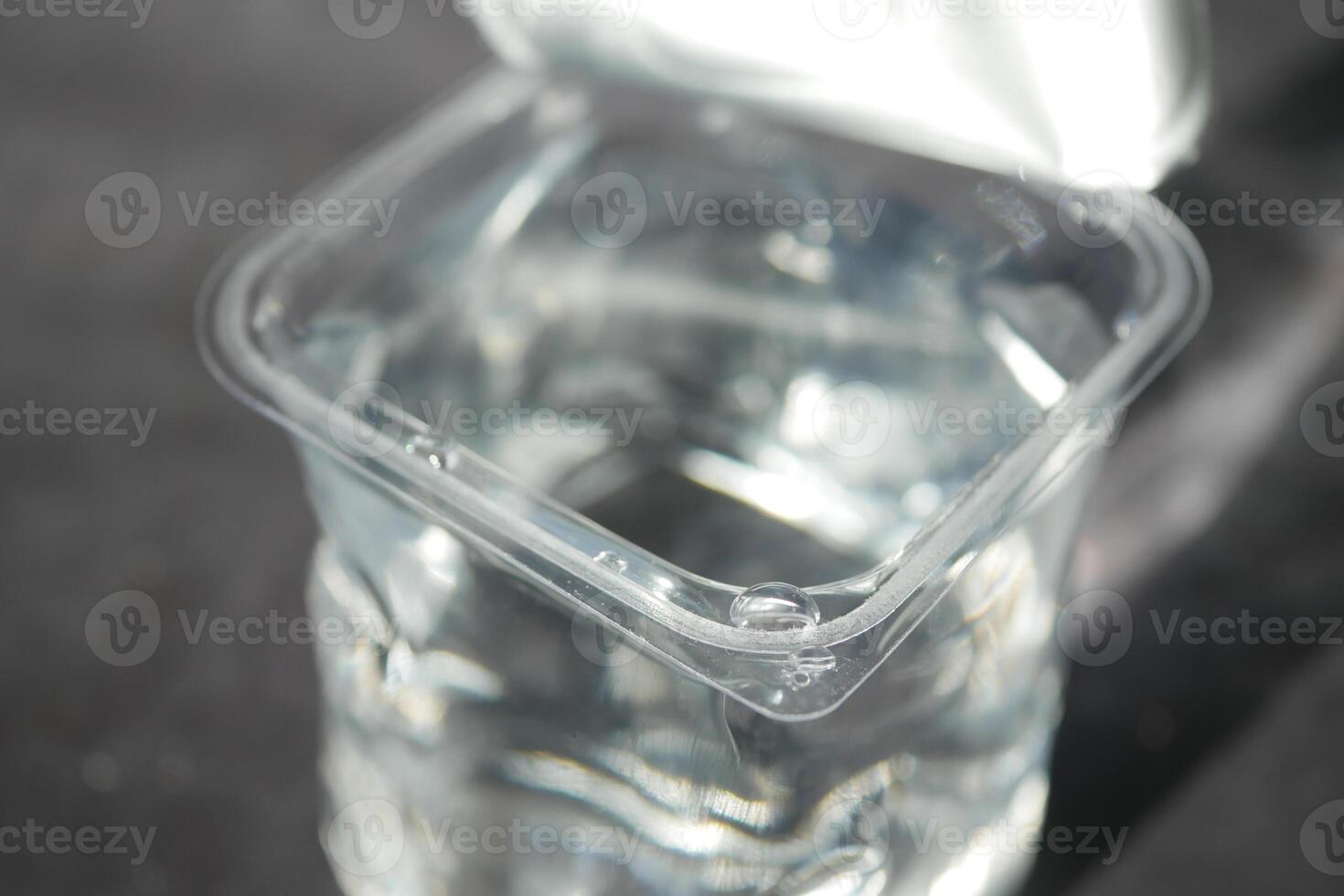 Clear container filled with water on a dark surface in daylight photo