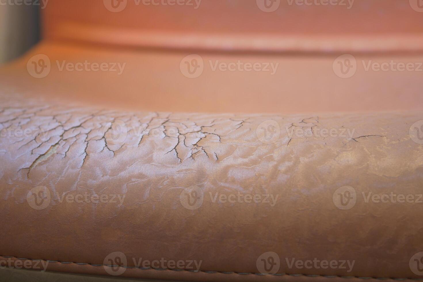 Cracked leather upholstery on a chair shows signs of wear and tear photo