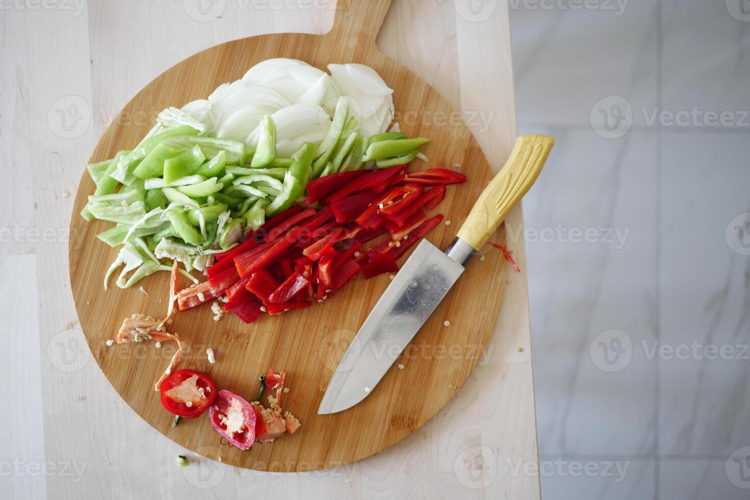Fresh vegetables being chopped on a wooden cutting board photo