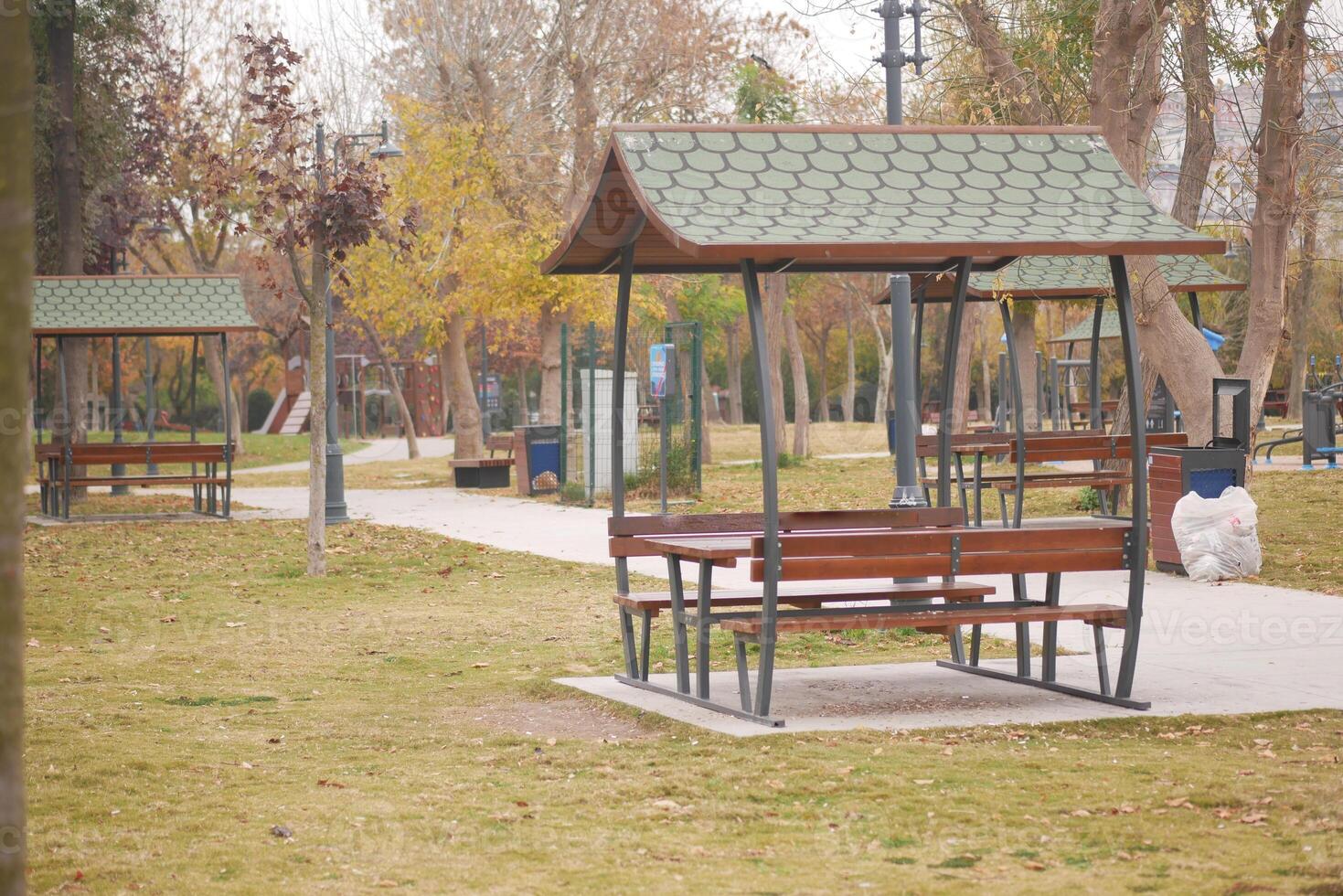 Deserted park with wooden shelters and empty benches in autumn photo