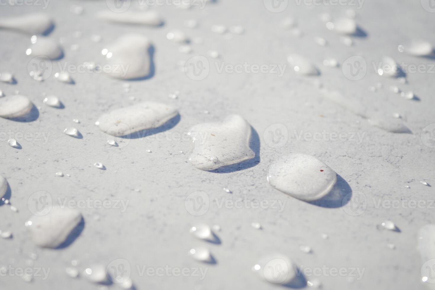 Water drops reflect light on a smooth surface under daylight photo