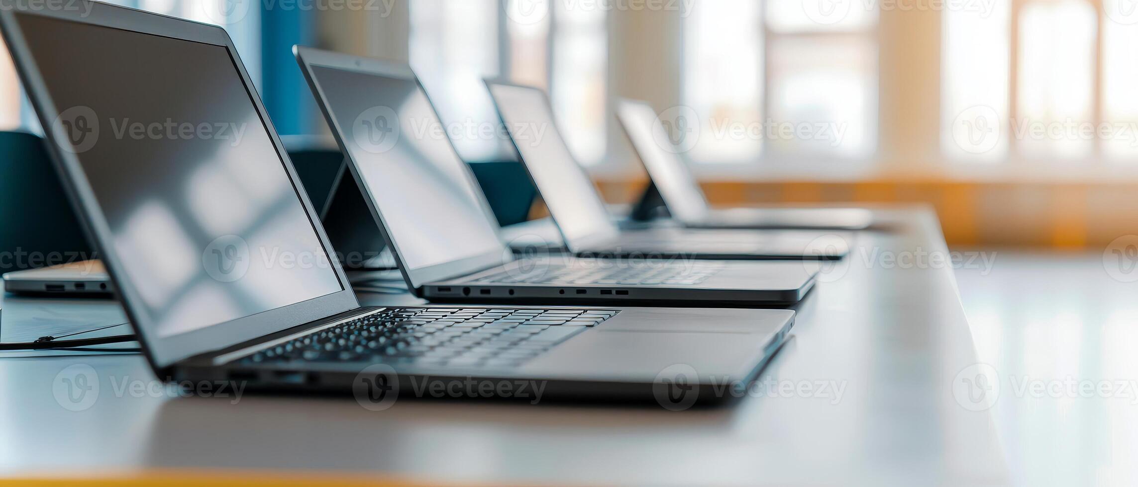 Higher education and collaboration degree concept. Modern laptops lined up on a table in a bright workspace. photo