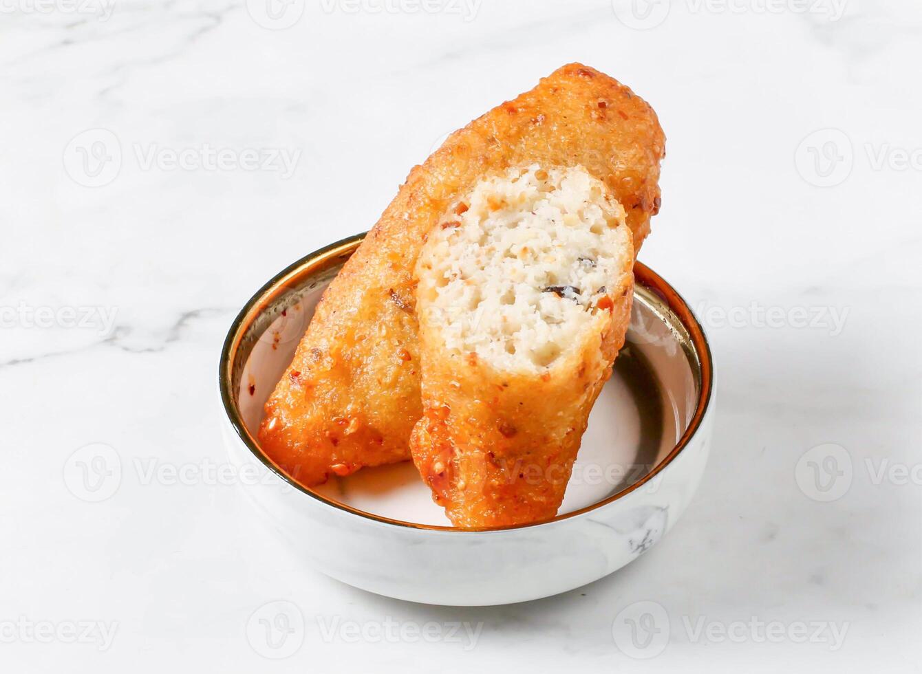 crispy coconut fritters served in small bowl isolated on marble background side view of singapore food photo
