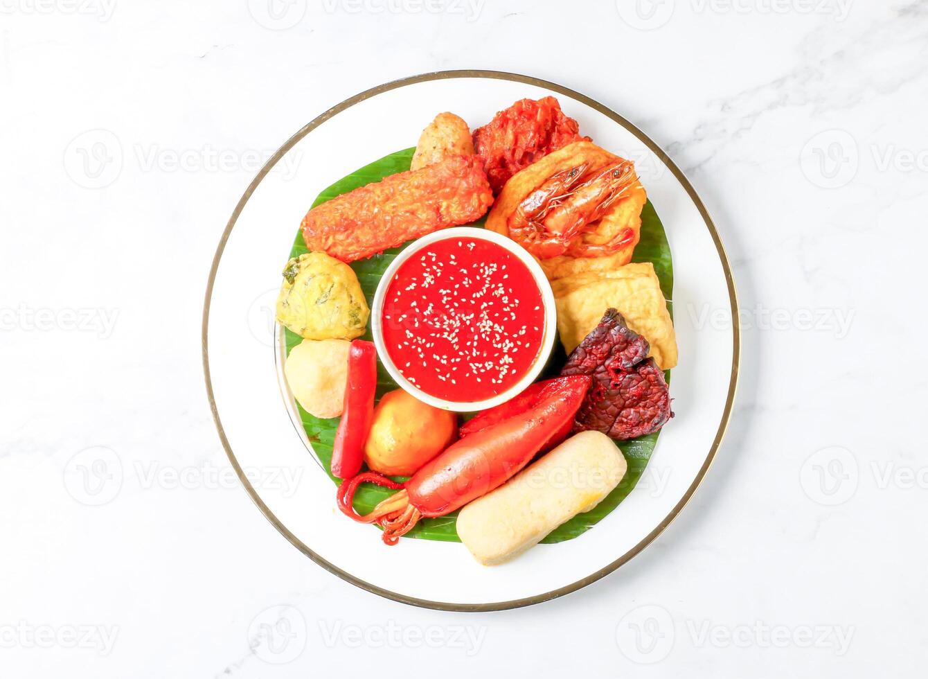 Malaysian Rojak set with Peanut Sauce, fried fritters, vegetables, tofu and banana leaf served in plate isolated on marble background top view of singapore food photo