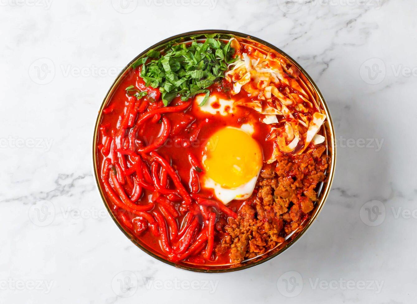 Mee Kuah with noodles, egg, sauce and herbs served in bowl isolated on marble background top view of singapore food photo
