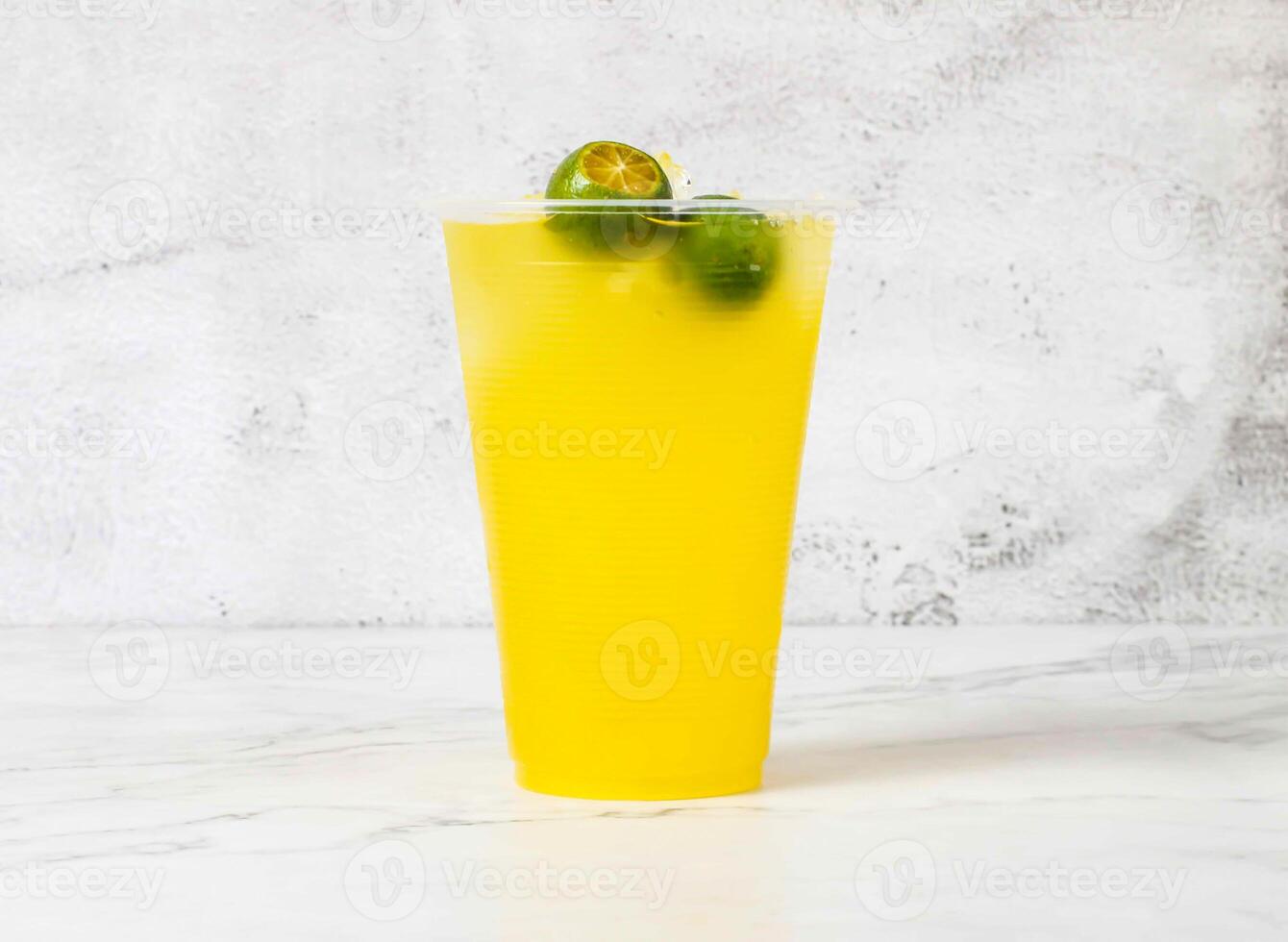 Refreshing Calamansi Lime Drink with ice cubes served in plastic cup isolated on marble background side view of Singapore beverage photo