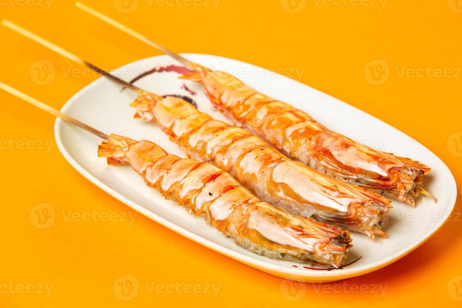 Grilled Tiger Prawns Skewers with salt served in plate isolated on orange background side view of hong kong food photo