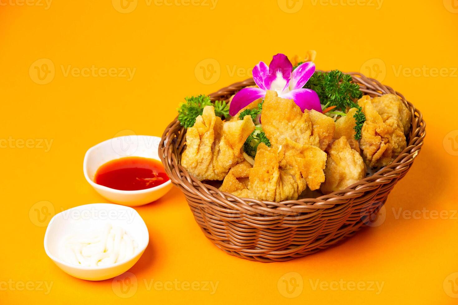 Crispy Fried Wontons with Dipping Sauces served in basket isolated on orange background side view of hong kong food photo