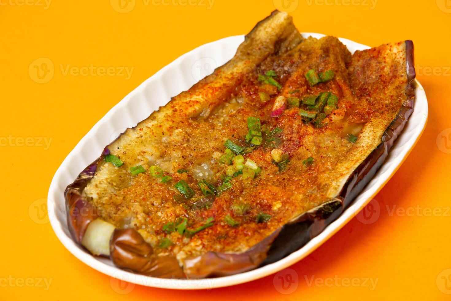 Grilled Japanese Eggplant with garlic and chopped scallions served in plate isolated on orange background side view of hong kong food photo