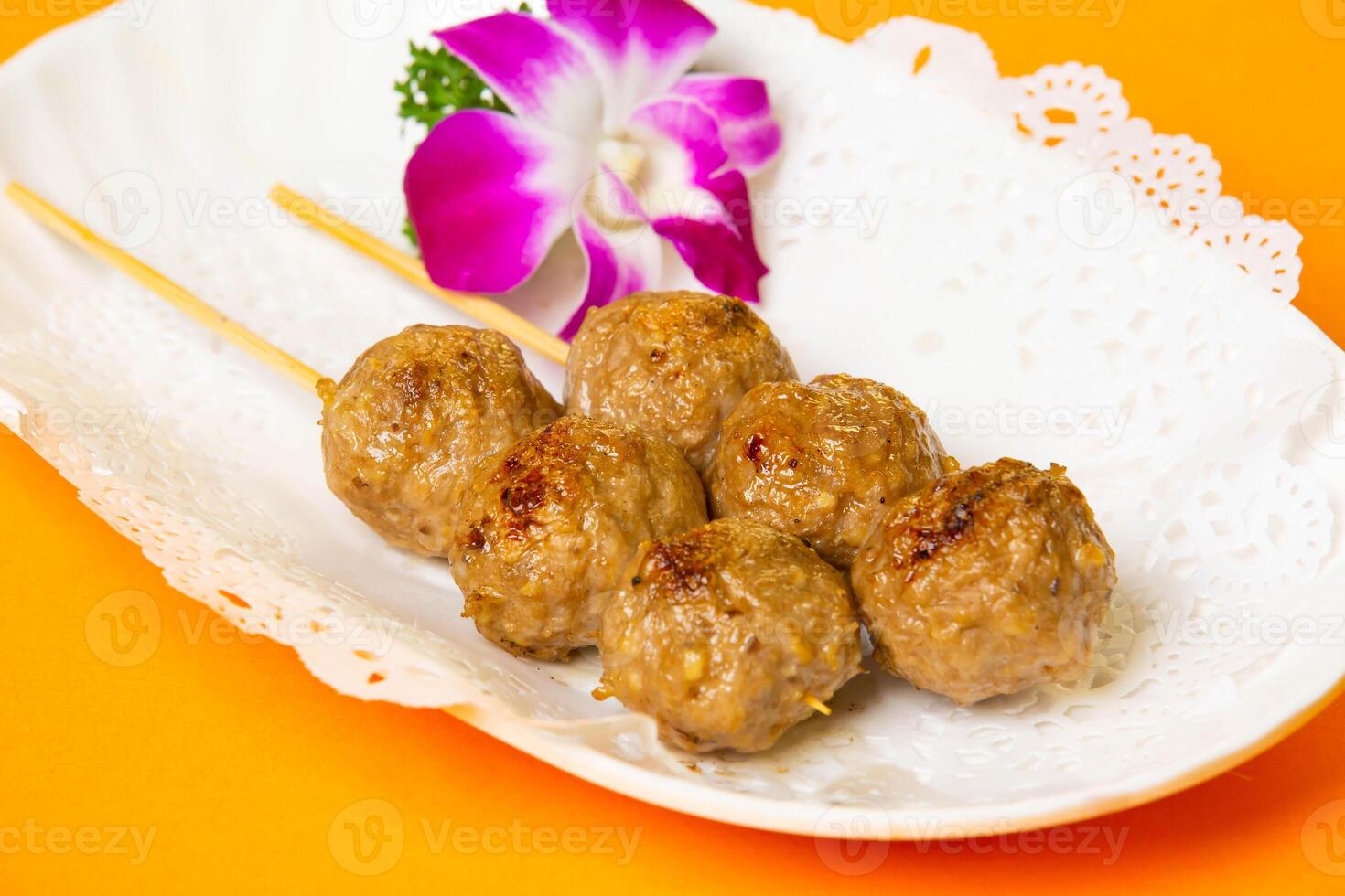 Roasted Beef Balls on Skewers served in plate isolated on orange background side view of hong kong food photo