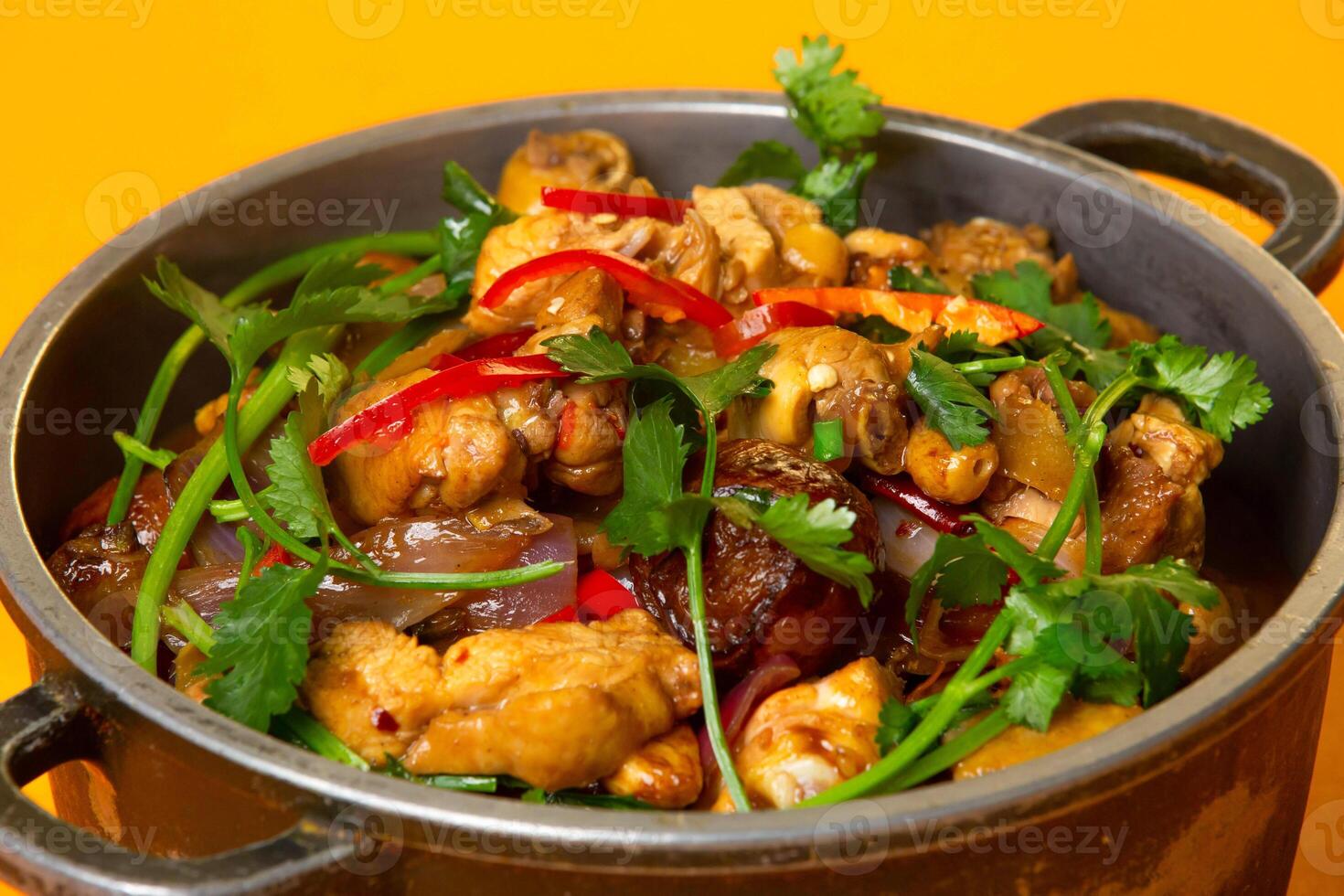 Chinese Spicy Chicken Pot topped with coriander served in pot isolated on orange background side view of hong kong food photo