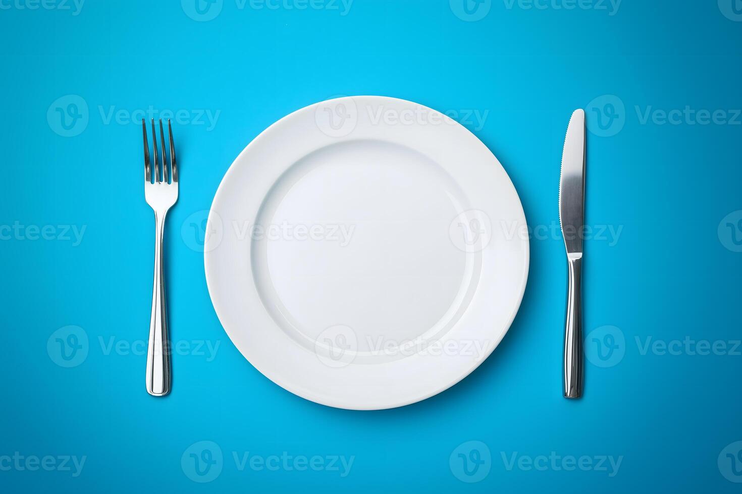 Empty plate, fork and knife on blue background photo