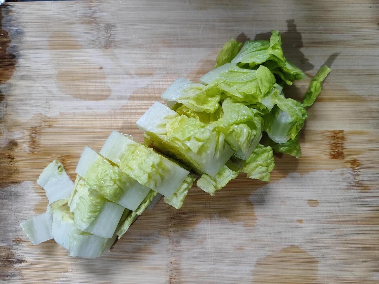 Freshly cut Romaine hearts lettuce on a wooden cutting board, showcasing vibrant green leaves. Perfect for healthy eating, salad recipes, or culinary presentations. photo