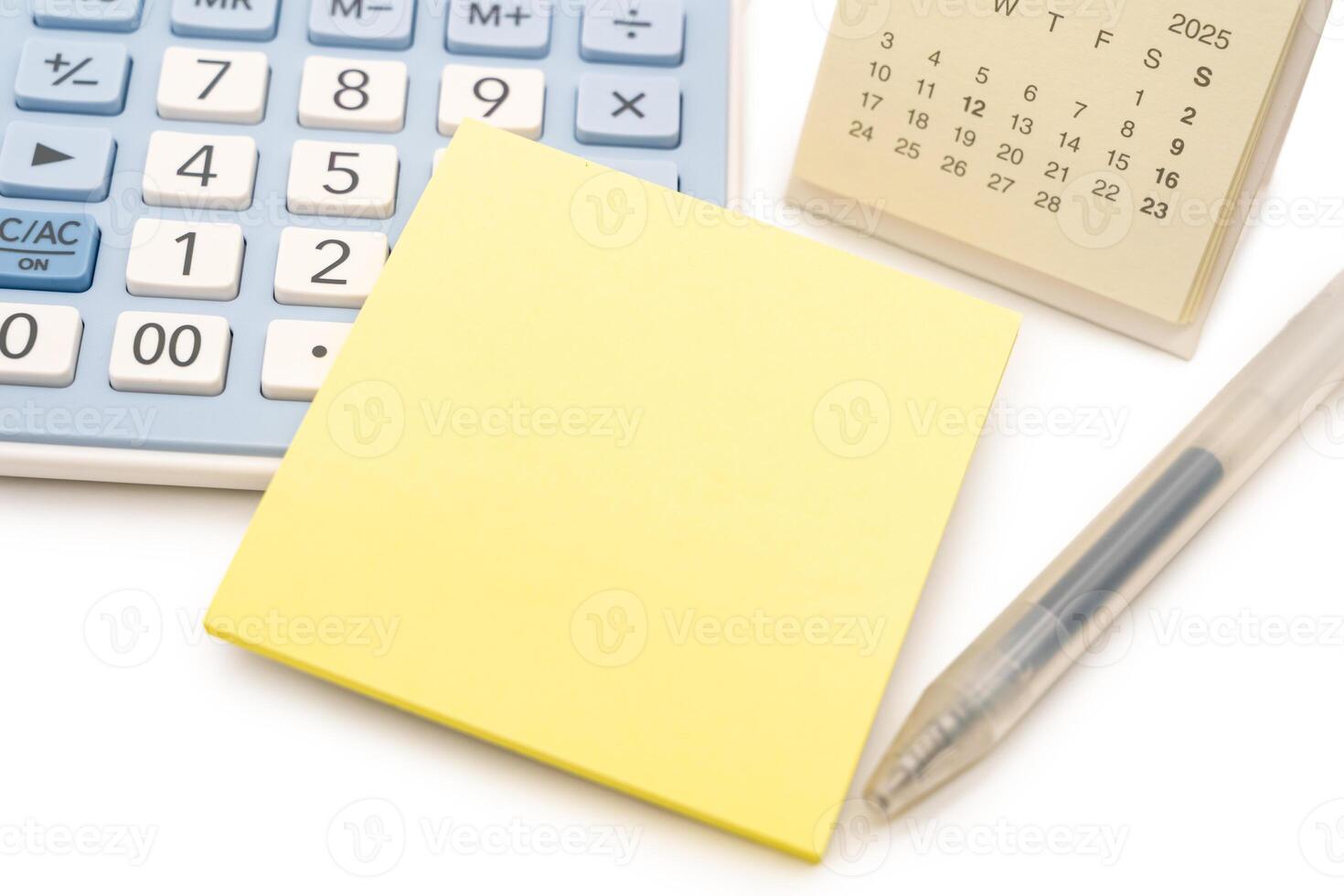 Blank Yellow Sticky note with calculator and calendar background. Financial data analyzing. Copy space for text on sticky note. isolated on white background. photo