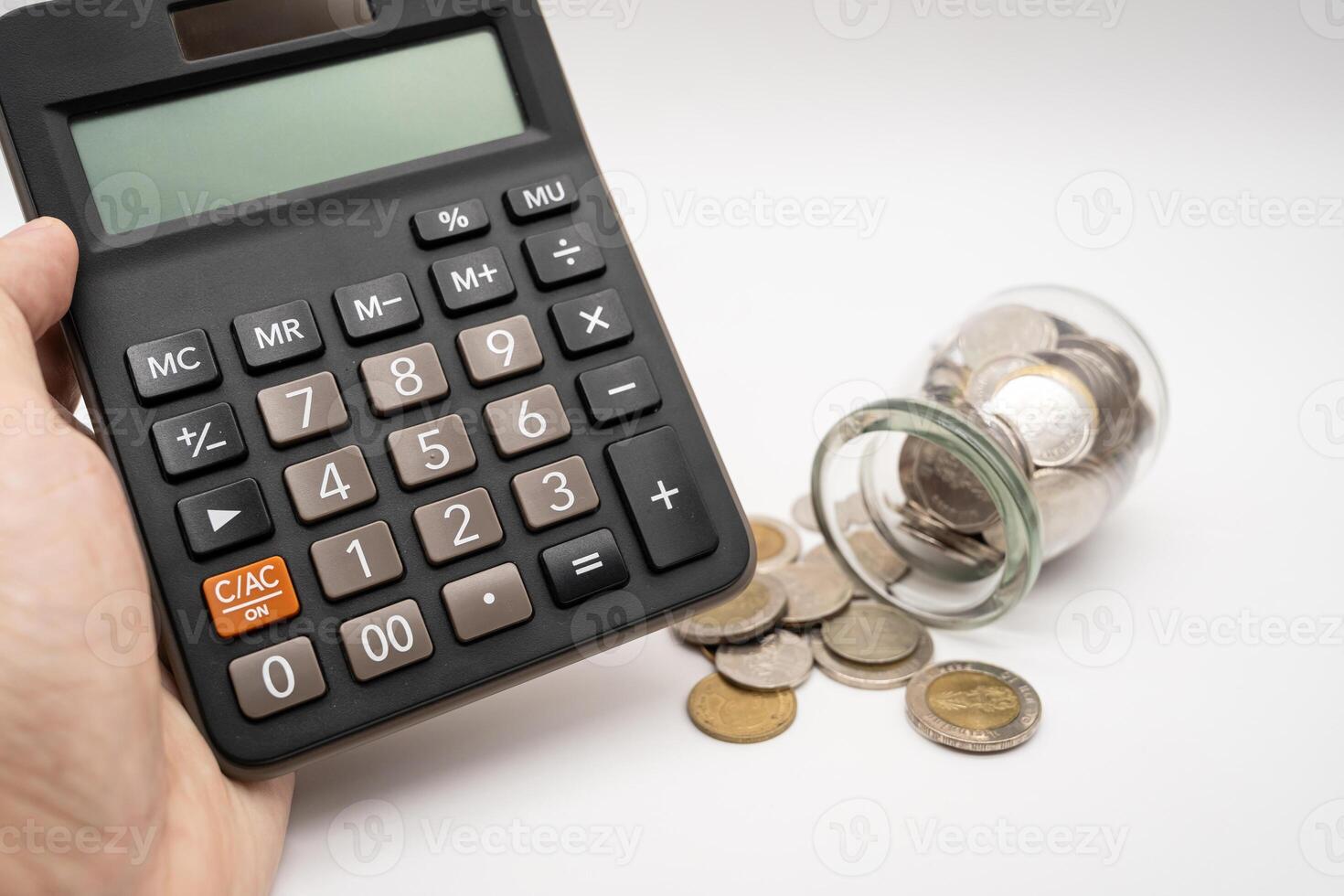 Thai Baht Coins spilled out of jar glass and Calculator with hand isolated on white background, saving for future, Investment business concept. photo