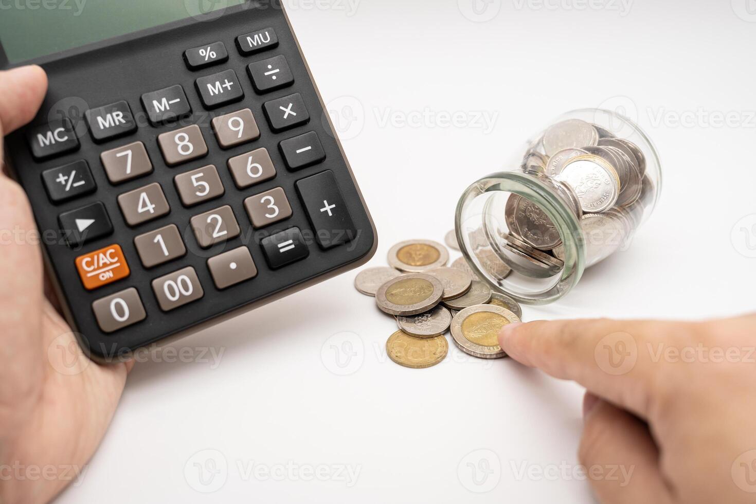 Thai Baht Coins spilled out of jar glass and Calculator with hand isolated on white background, saving for future, Investment business concept. Business and Financial Concept. photo