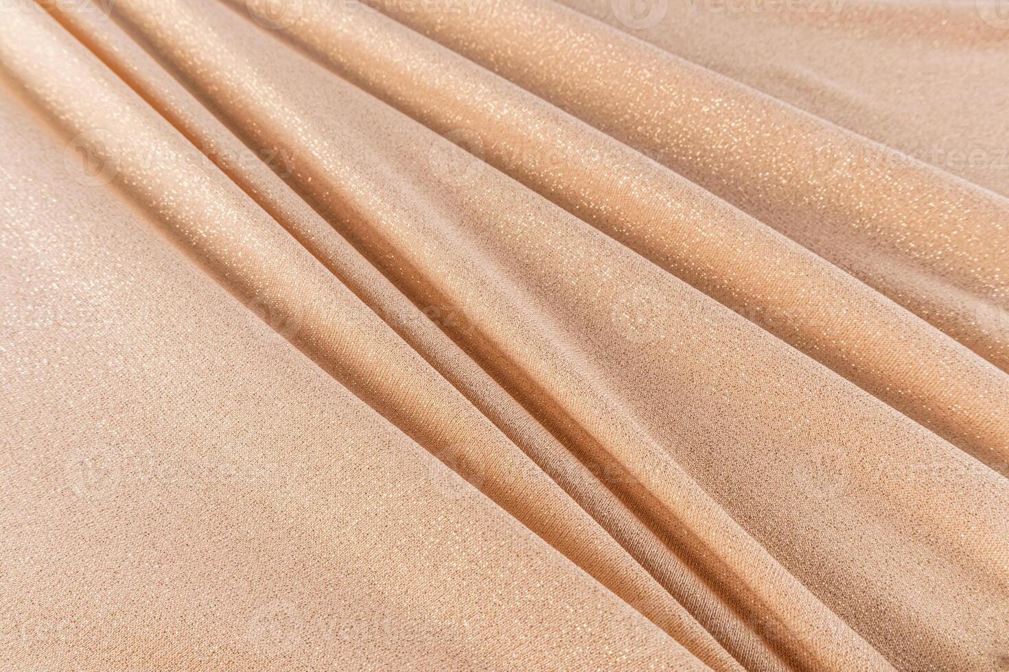 The texture of beautiful soft folds of gold dense fabric with glitter. The concept of festive, wedding, New Year's background. layout. design. photo