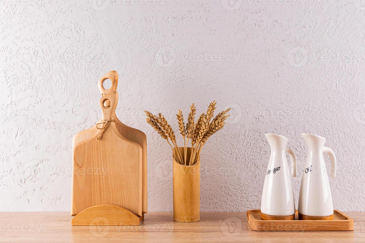 Two stylish bottle oil and sauce storage on a wooden stand on a wooden countertop. a set of kitchen boards, vase of ears. minimalism. Front view photo