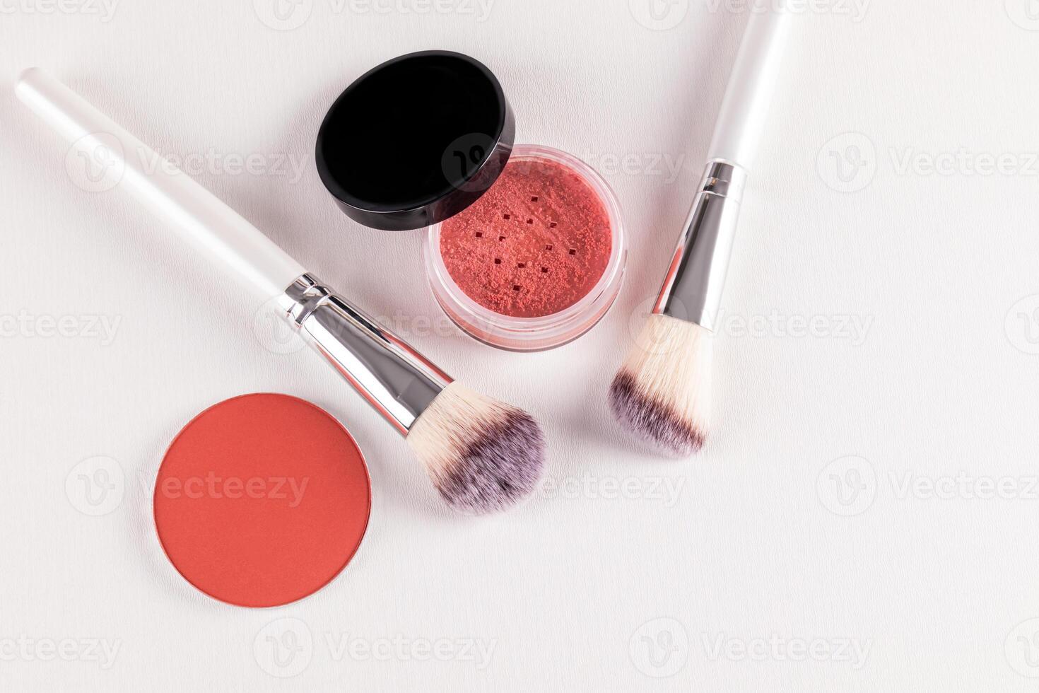 Two chic makeup brushes and two blush in an open jar, a pink tone block on a white embossed background. top view. A copy space. The concept of beauty. photo