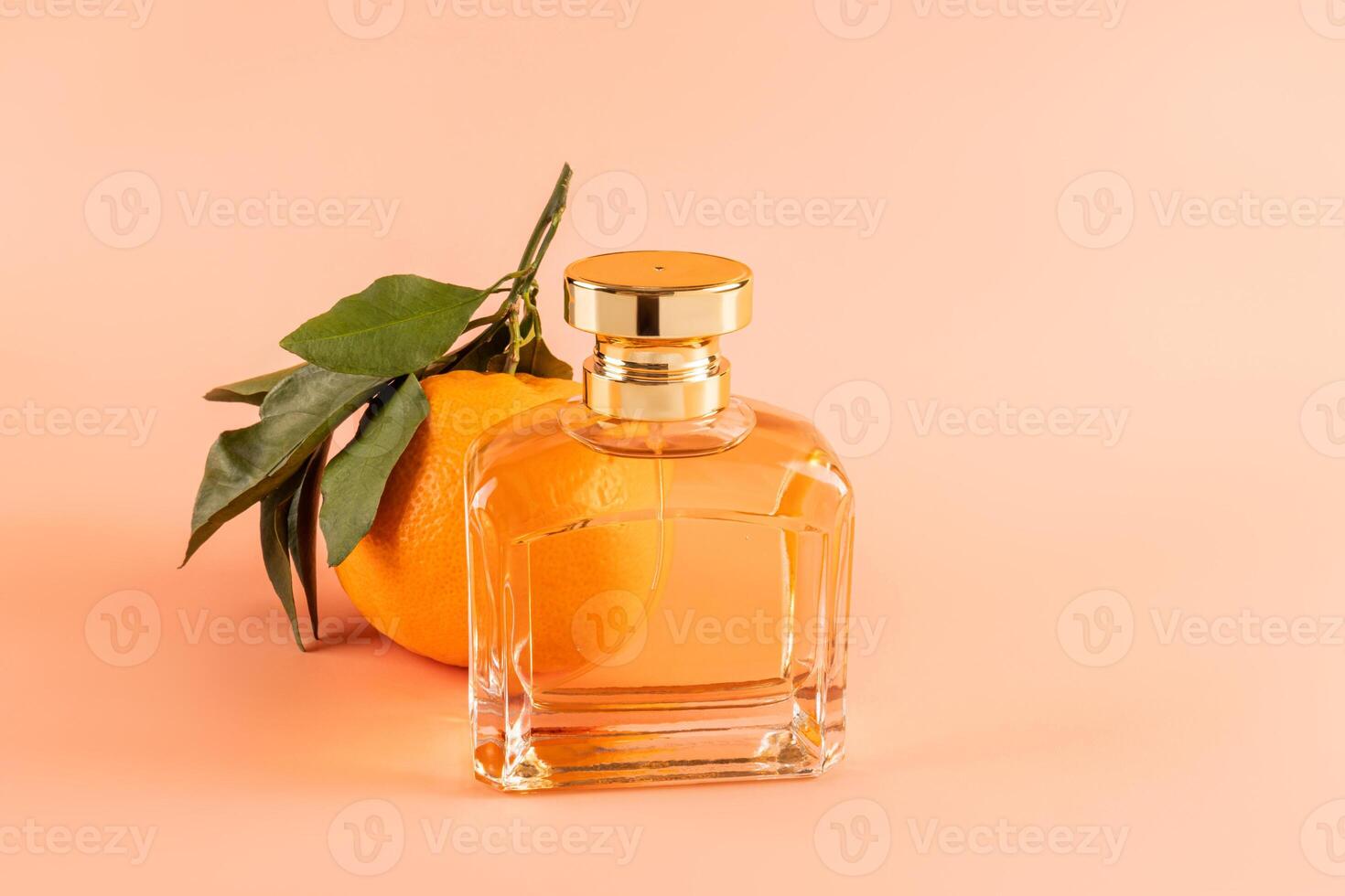 A chic bottle with a gold cap with cosmetic spray, perfumery with the aroma of citrus fruits on a background of tangerine with leaves. Front view photo