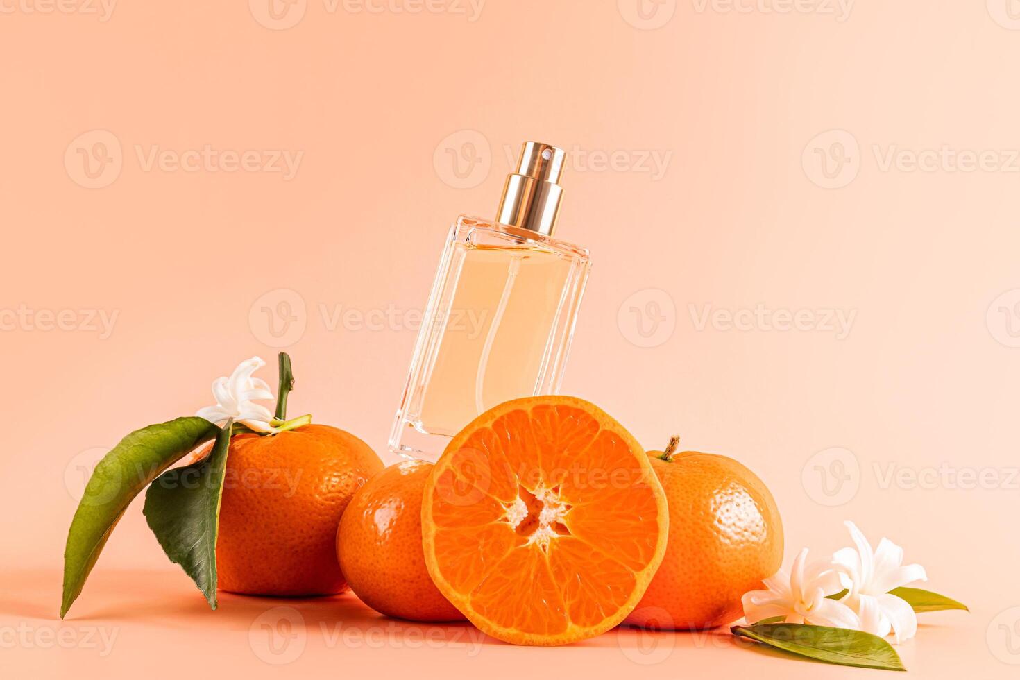 A transparent bottle of cosmetic spray, perfume, lotion with the smell of citrus stands on juicy tangerine fruits with leaves and flowers. Front view. photo