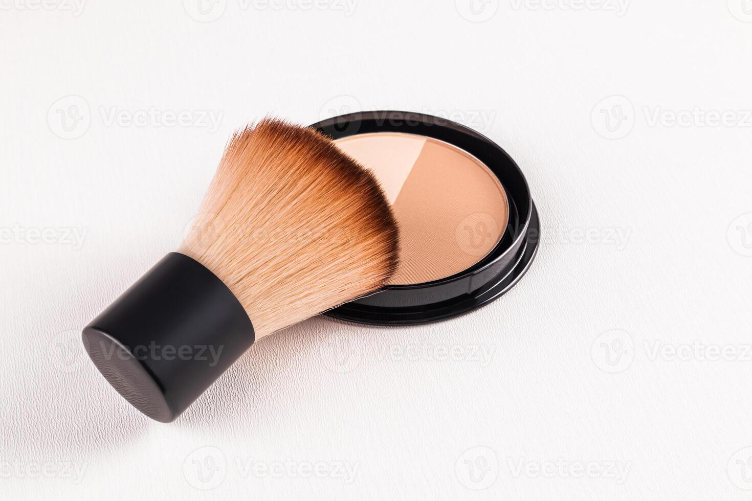 A fluffy short makeup brush rests on a block of compact powder with two different tones. An open pack of powder. texture of decorative cosmetics. photo