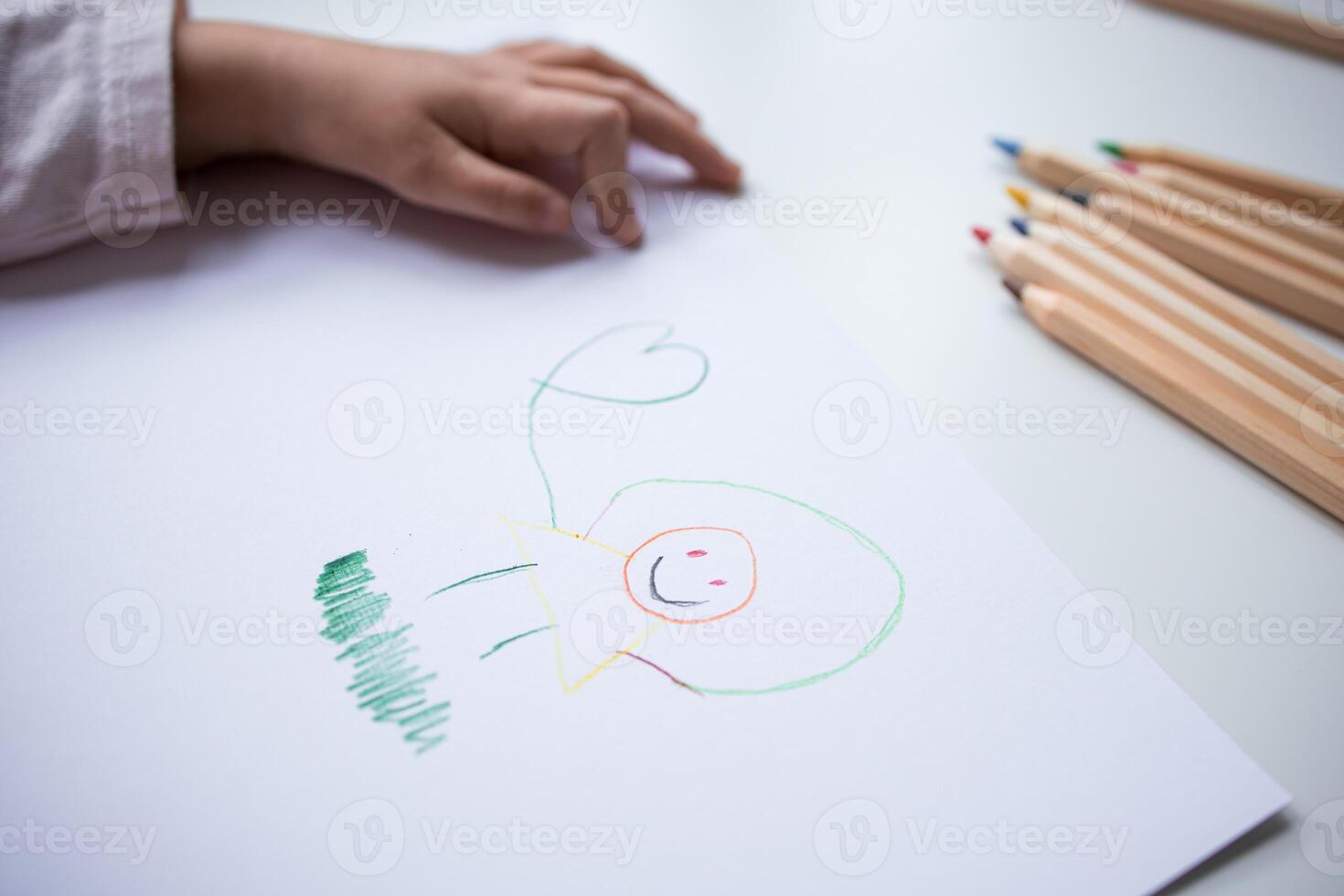Childs colorful drawing on paper with pencils nearby photo