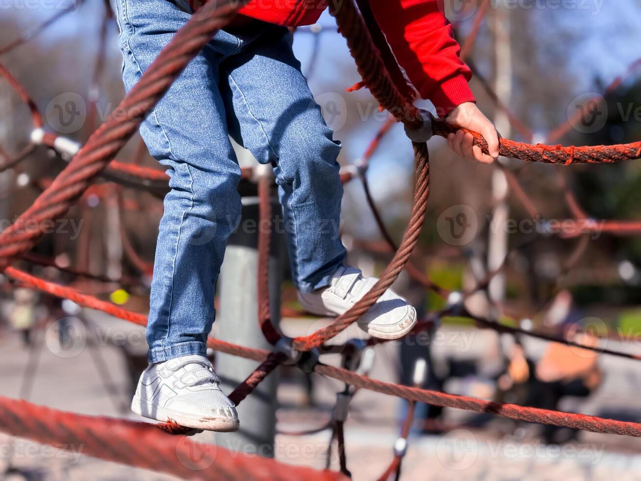 Child climbing on playground rope structure in park photo