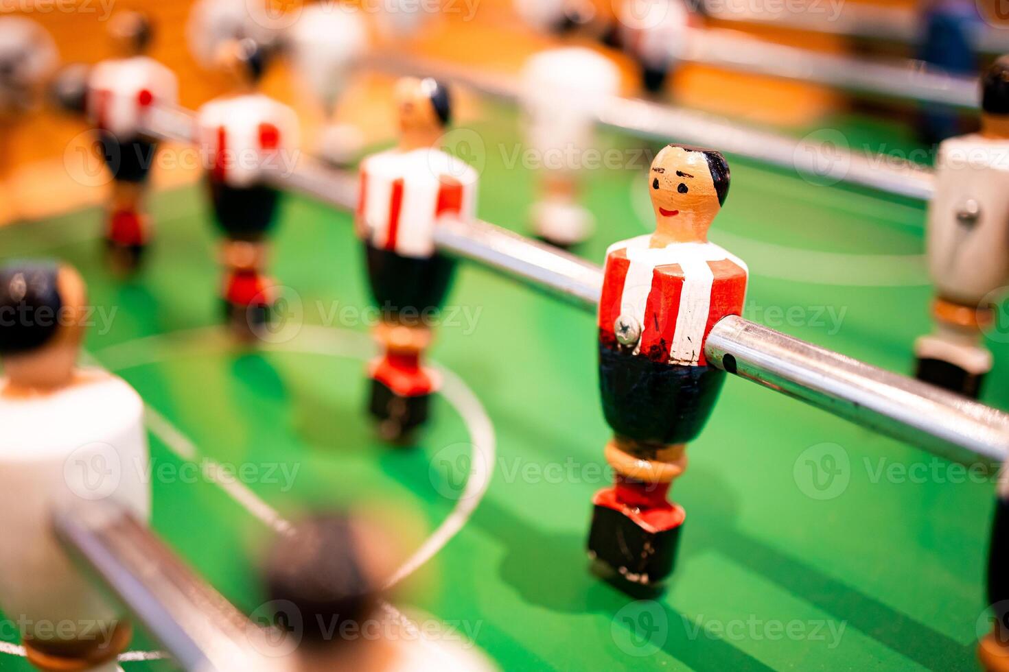 Foosball table close up with red and white figures on green field photo