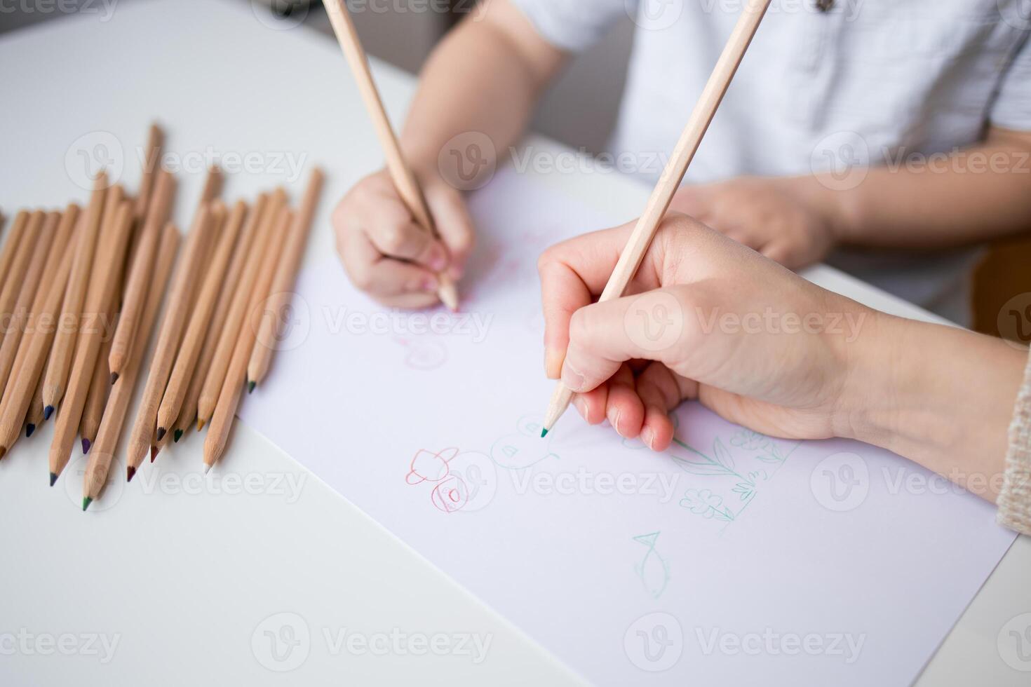 Young child and adult drawing with colored pencils on paper photo