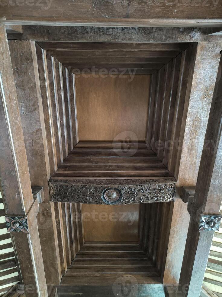 The wooden ceiling of a traditional Javanese luxury house and decorated with carved ornaments. photo
