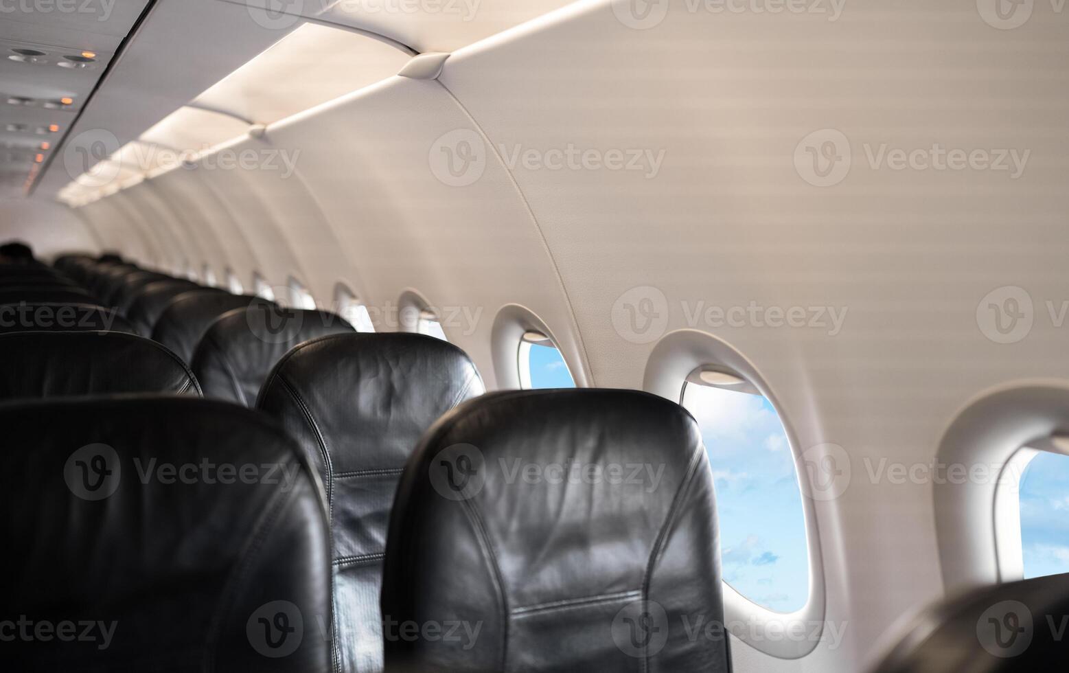 Airplane cabin interior,Empty comfortable row seats in economy class with portholes,Aerial view through airplane window,Inside Passenger plane looking out at cloud sky,Concept for transport Travel photo