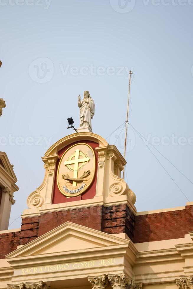 A building with a clock and a statue on top photo