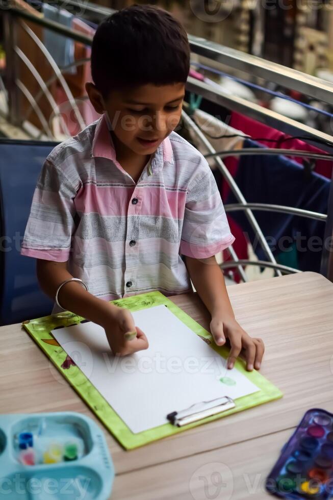 A young boy is drawing on a piece of paper photo