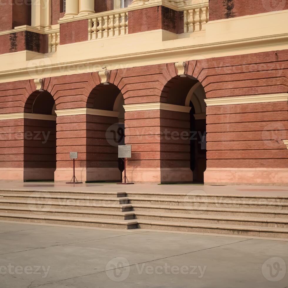 A man is sitting on a bench in front of a building photo