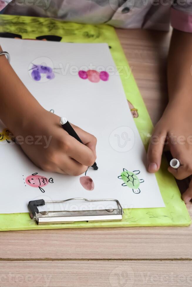 A child drawing on a piece of paper with a pen photo
