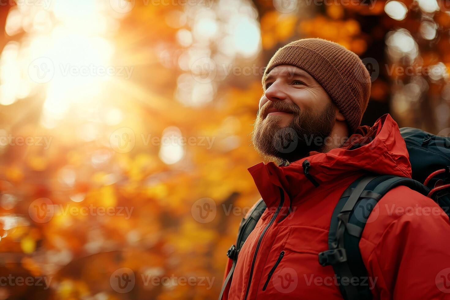 a Male Hiker Surrounded by Vibrant Fall Forest Sunlight Filtering Through Trees and Illuminating the Trail photo
