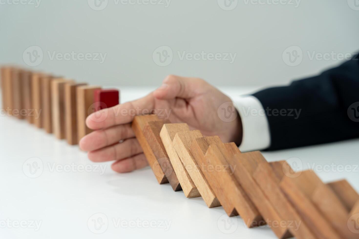 Businessman hands stop dominoes falling in business crisis. business risk control and planning and strategies to run prevent insurance. photo