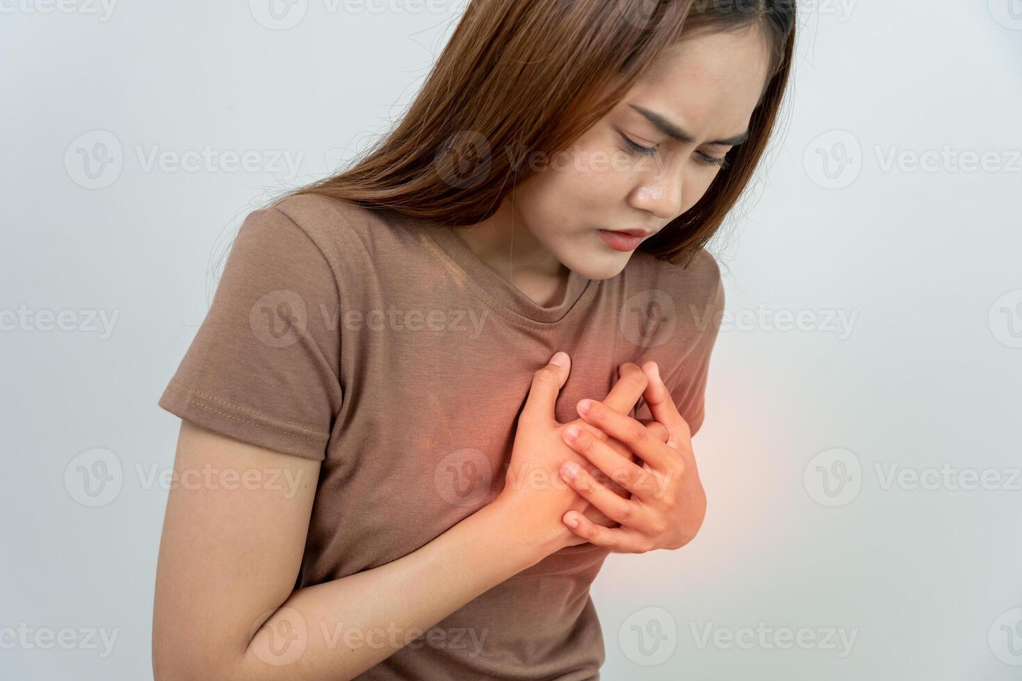hand hold chest with heart attack symptoms, asian woman have chest pain caused by heart disease, leak, dilatation, enlarged coronary heart, press on the chest with a painful expression. photo
