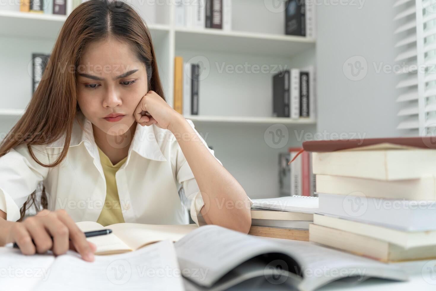Asian student woman have anxiety because of exams, female prepare for test and learning lessons in the library. stress, despair, haste, misunderstanding reading, discouraged expectation. photo